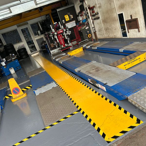 Empty vehicle inspection bay with bright yellow safety markings and equipment.
