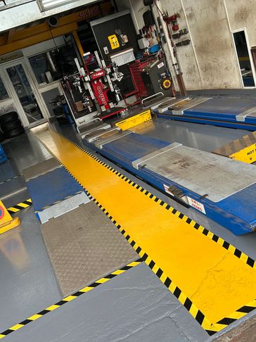 Empty vehicle inspection bay with bright yellow safety markings and equipment.