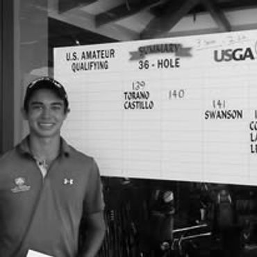 Young golfer standing beside a U.S. Amateur Qualifying scoreboard.