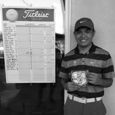 Young golfer proudly holds a badge next to a Titleist golf scorecard.
