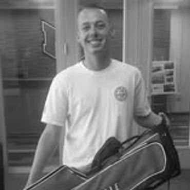 Young man smiling while holding a red Maryville bag indoors.