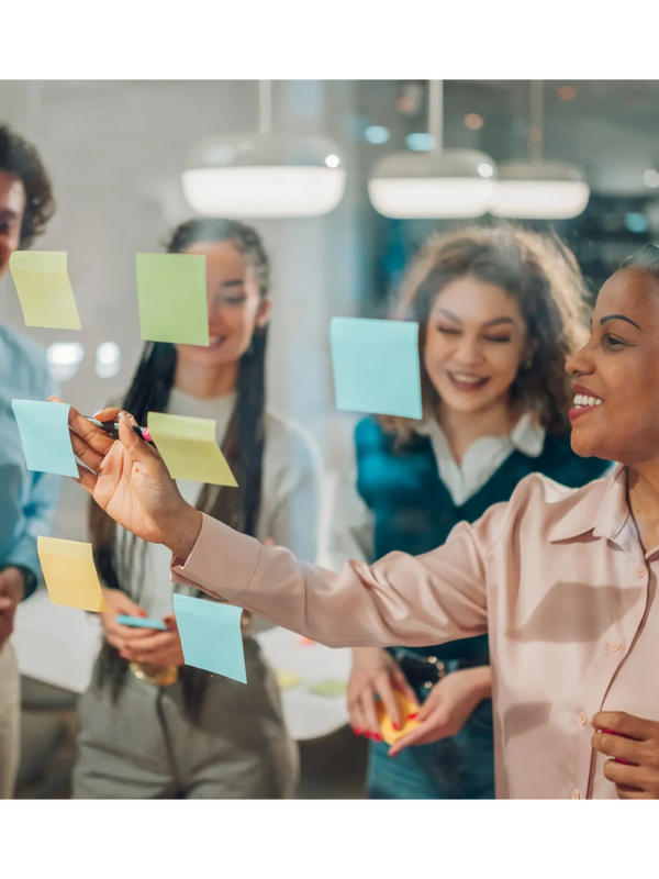 Team collaborating and brainstorming with sticky notes on glass wall.