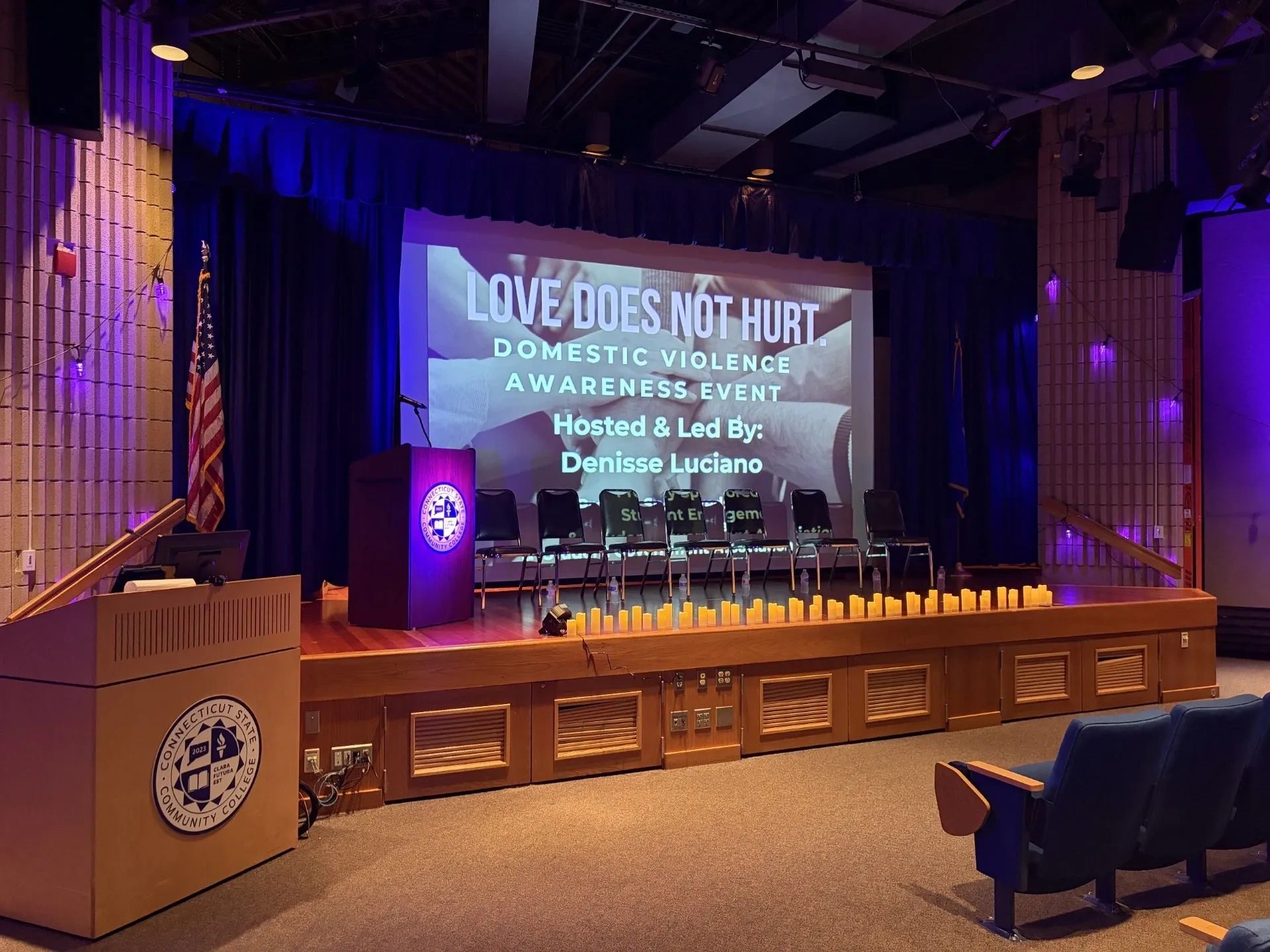 Stage set for a domestic violence awareness event with candles and a podium.