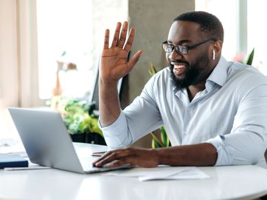 Man waving during a video call on his laptop.