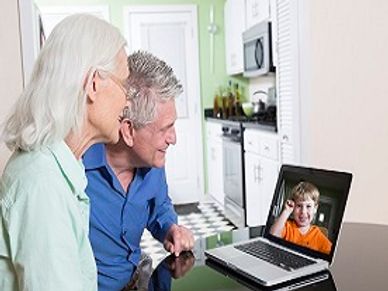 Elderly couple video calling a young boy on a laptop.
