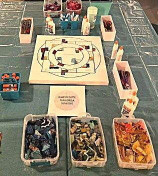 Community mandala making setup with colorful paper pieces and glue.