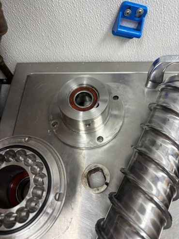 Disassembled metal machinery parts on a stainless steel surface.
