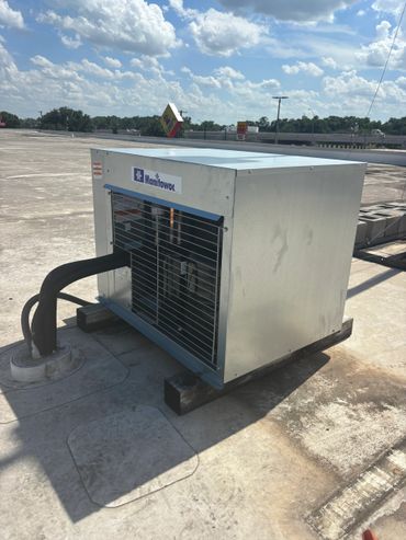 A Manitowoc HVAC unit installed on a rooftop under a blue sky.