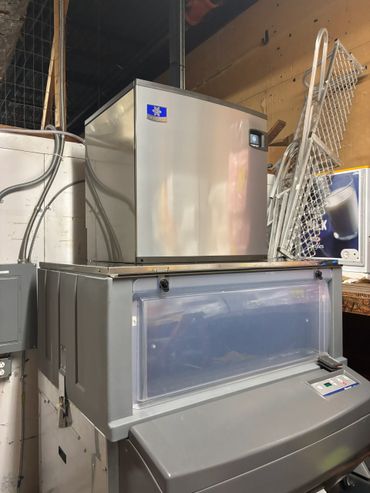 Large commercial ice machine in a utility room with cleaning carts.