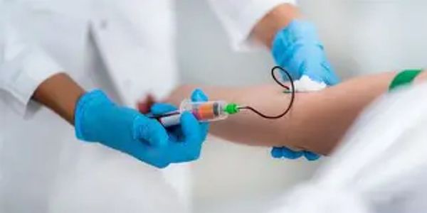 Healthcare worker drawing blood from a patient's arm with a syringe.