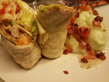  A spicy chicken wrap on a plate with a salad