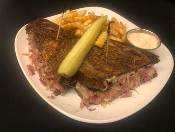 Reuben sandwich  and French Fries on a plate with a dipping sauce