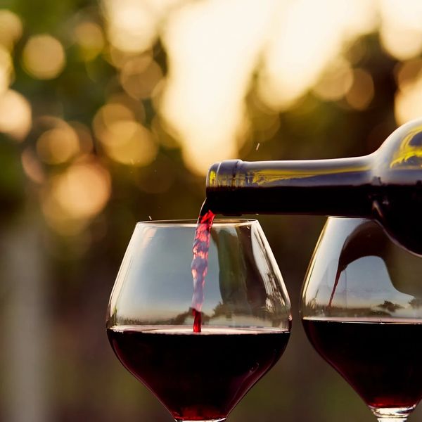 Red wine being poured into a glass during sunset.