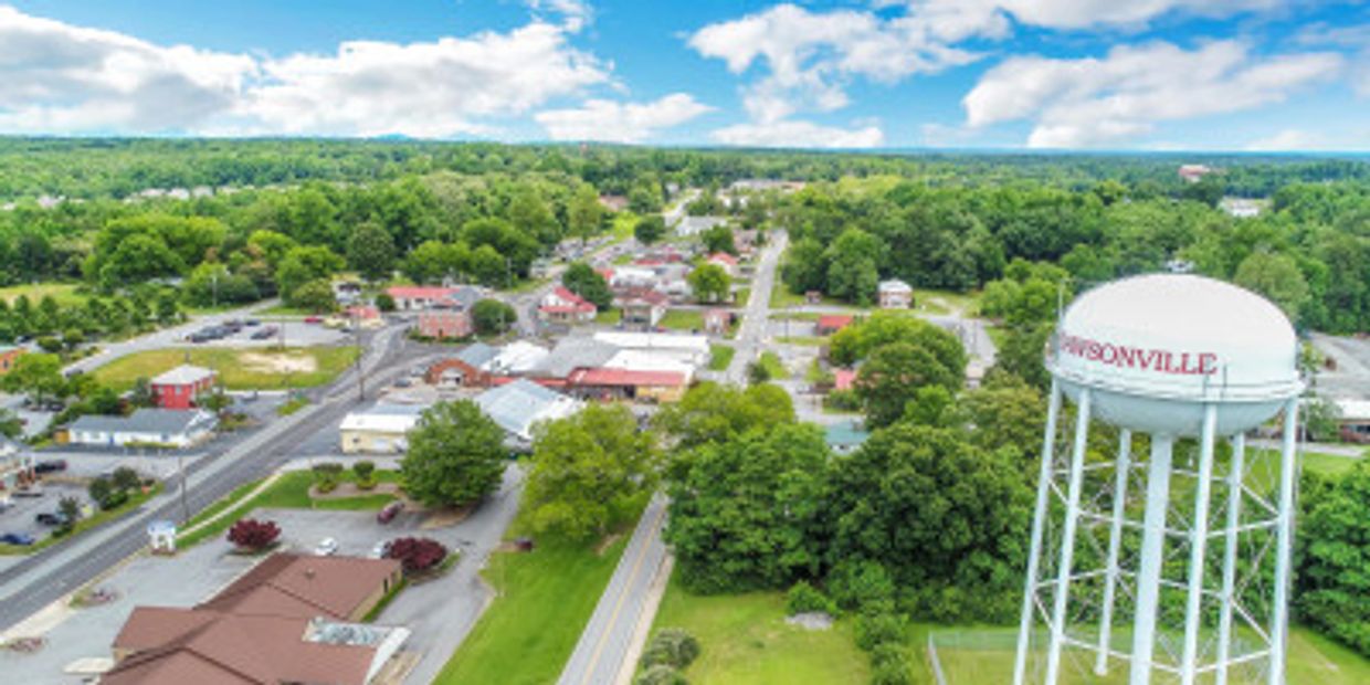 A water tower stands tall overlooking a Dawsonville GA town with greenery and roads.