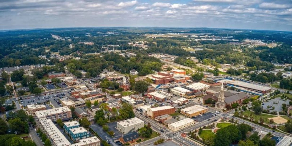 Aerial view of a small town with local moving services roads, and greenery under a cloudy sky.