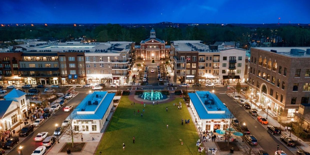 A vibrant town square at night with lit fountains and people enjoying the evening stress-free relocation.
