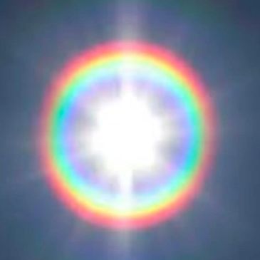 Bright sun with a vivid rainbow halo against a blue sky.
