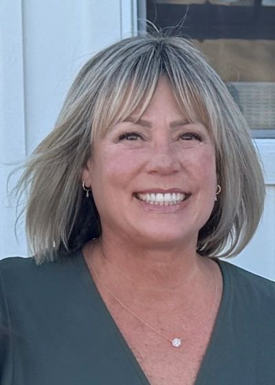Smiling woman with short blonde hair outdoors.