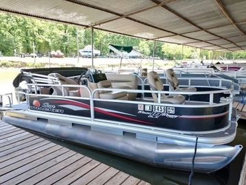 Pontoon boat docked under a covered marina.