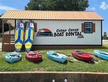 Kayaks and paddleboards displayed outside Cedar Creek Boat Rental.