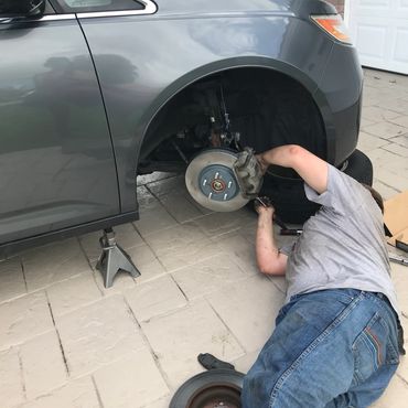 Person working on a car's brake system with the wheel removed in Tampa Bay.