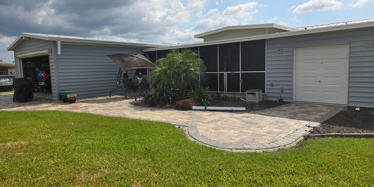 Suburban house with a well-maintained lawn and patio under partly cloudy skies.