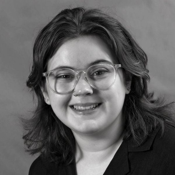 Smiling woman with glasses in black and white portrait.