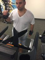 A man carrying weight on his wrists while walking on treadmill connect himself to the treadmill with the treadmill safety waist belt connect me tight belt