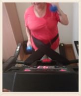 A woman holding weight dumbbells walking on a treadmill while connecting herself to the treadmill by the treadmill safety belt called connect me tight