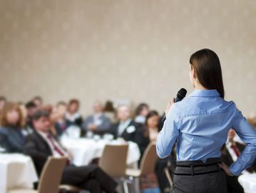 Female speaker holding a microphone and giving a speech at a business conference 