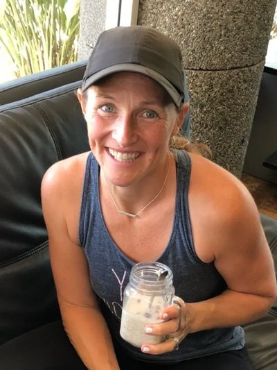 Smiling woman in a cap holding a jar drink.