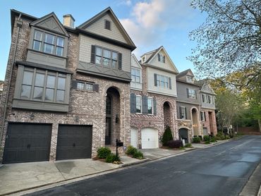 Row of modern townhouses with brick facades and garages on a quiet street.