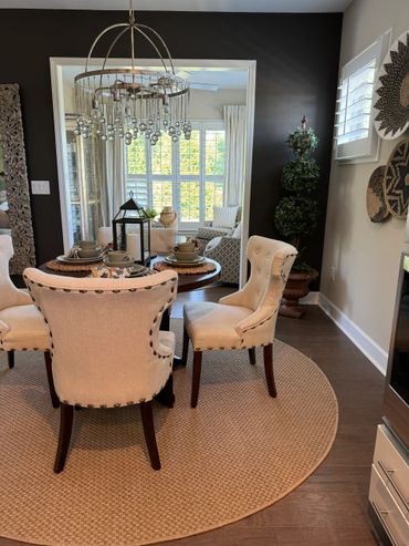 Cozy dining area with beige chairs and a round rug under a decorative chandelier.