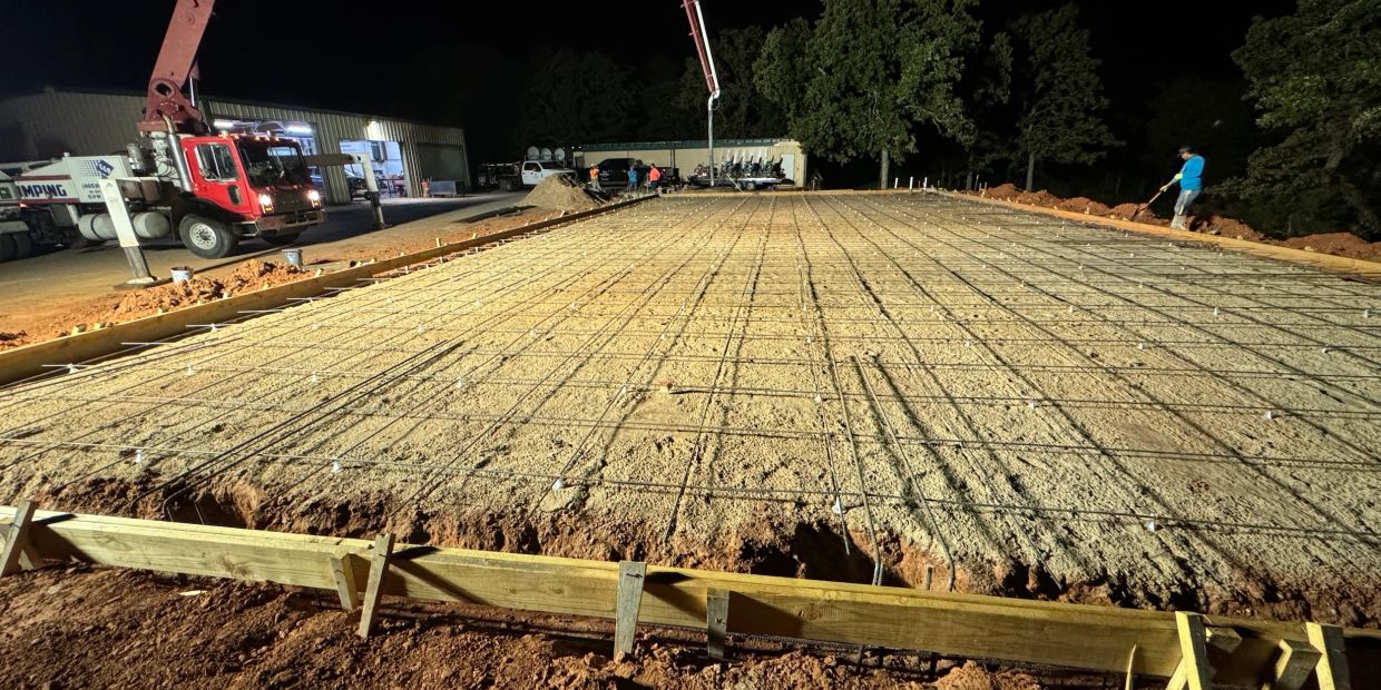Nighttime construction site with concrete foundation preparation.
