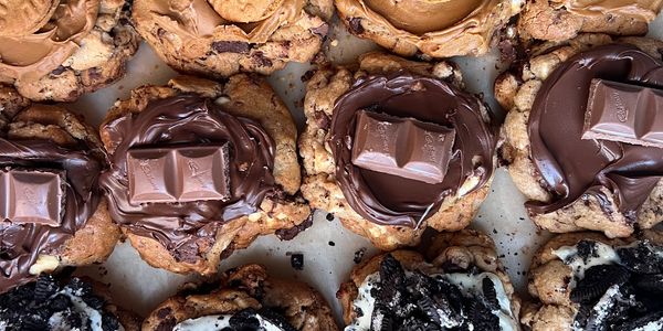 Assorted gourmet cookies with various toppings like chocolate, biscuits, and crushed oreos.