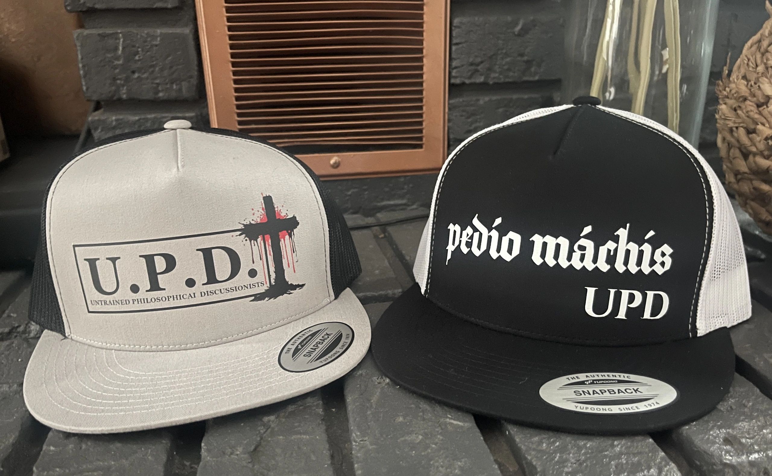 Two snapback hats with philosophical and Spanish text designs.