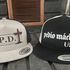 Two snapback hats with philosophical and Spanish text designs.