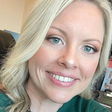 Close-up of a smiling woman with blonde hair and green eyes.
