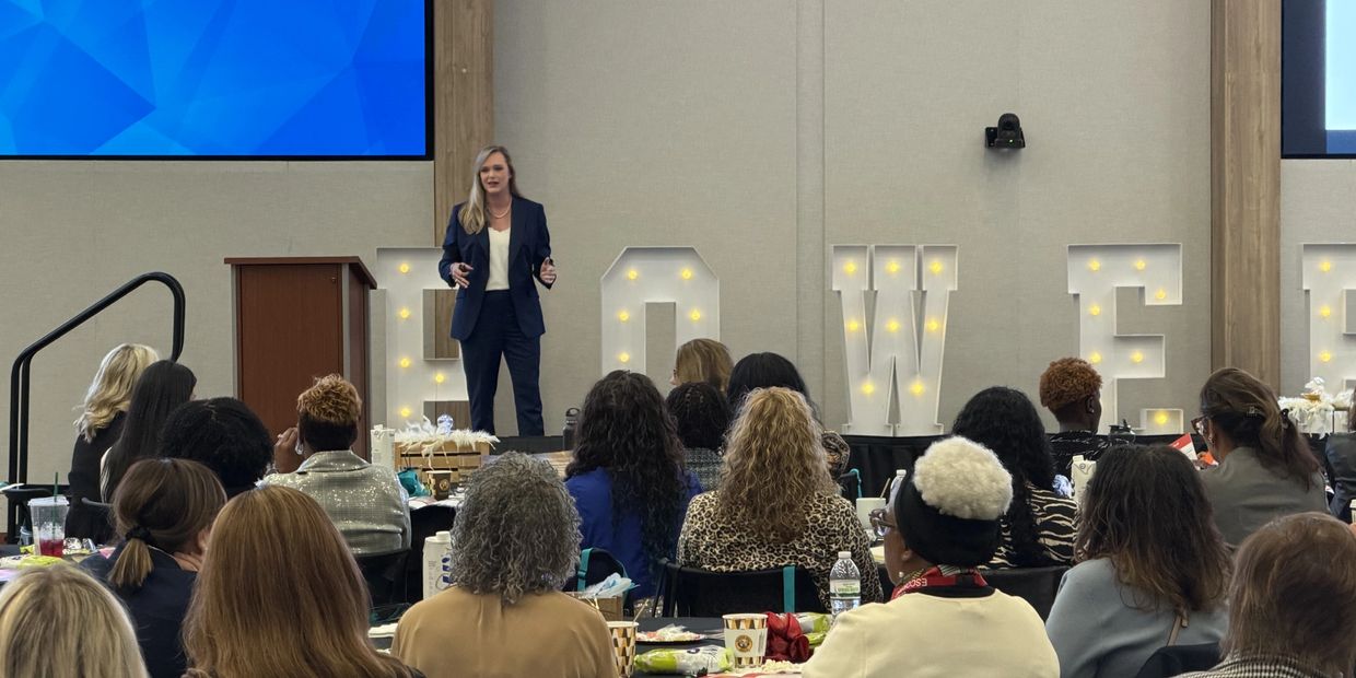 A woman speaks at a law-themed event with an attentive audience.