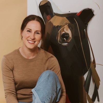 Woman smiling next to a bear artwork.