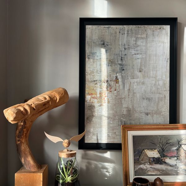 Detail of a styled console with wood sculpture and original art work on grey tones