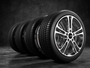 Four shiny car tires with polished rims arranged in a row.