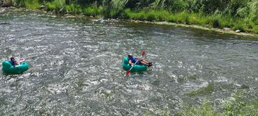 Two people floating on a river in inflatable tubes on a sunny day.