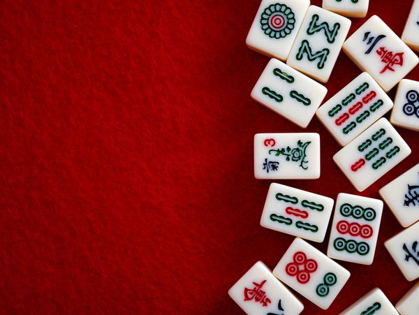 Mahjong tiles scattered on a red felt surface.