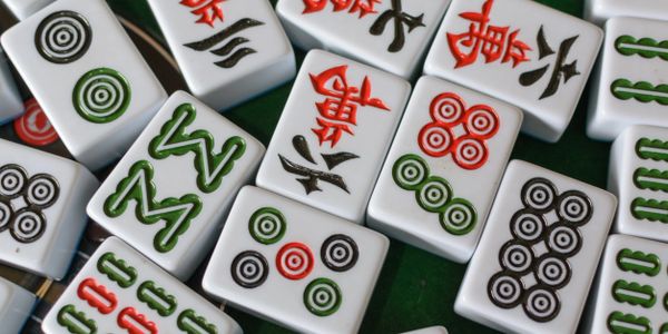 Close-up of colorful Mahjong tiles scattered on a green surface.