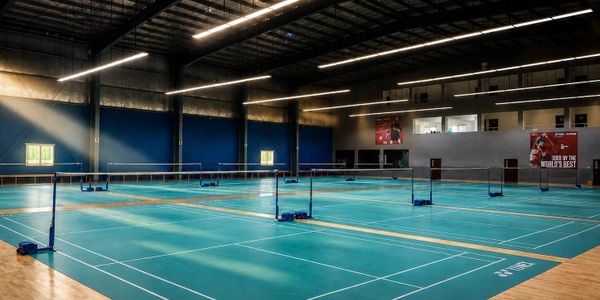 Empty indoor badminton courts with bright lighting.