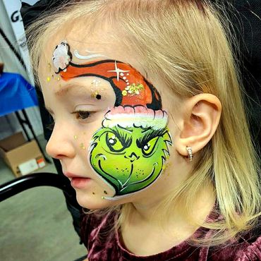 Beau maquillage du Grinch de Noël appliqué sur la joue par ka maquilleuse de Hugo Lemay Animation