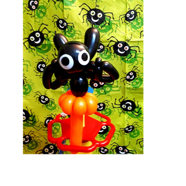 Sculpture de Ballons représentant une chauve souris noire aux yeux blancs sur fond vert d'halloween