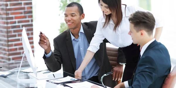Three business professionals collaborating around a computer in a modern office.