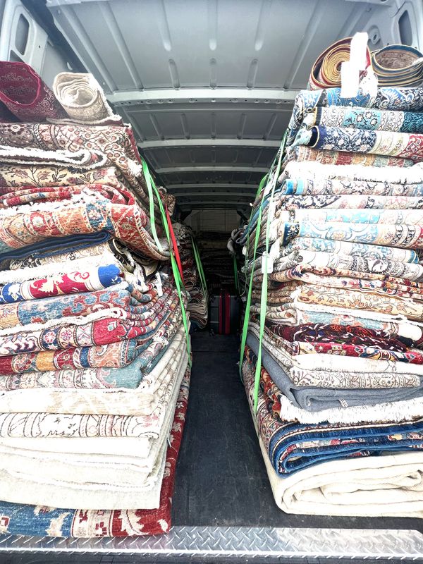 Stacks of patterned rugs neatly arranged inside a vehicle.